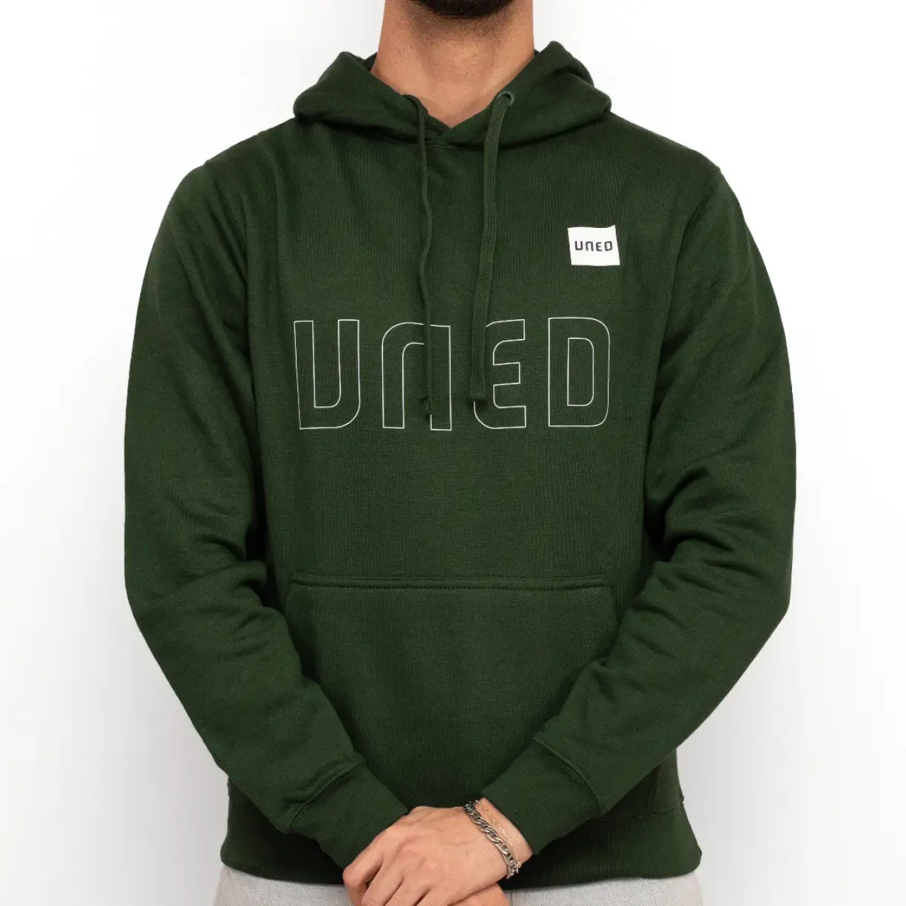 Sudadera con capucha en color verde con tipografía UNED en grande y parche UNED, vista frontal sobre modelo.